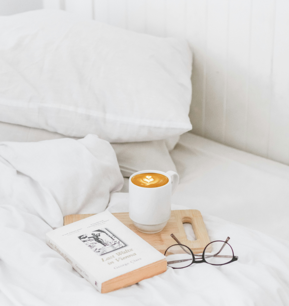 Książka, kawa i okulary umieszczone na łóżku z materacem na wymiar.
